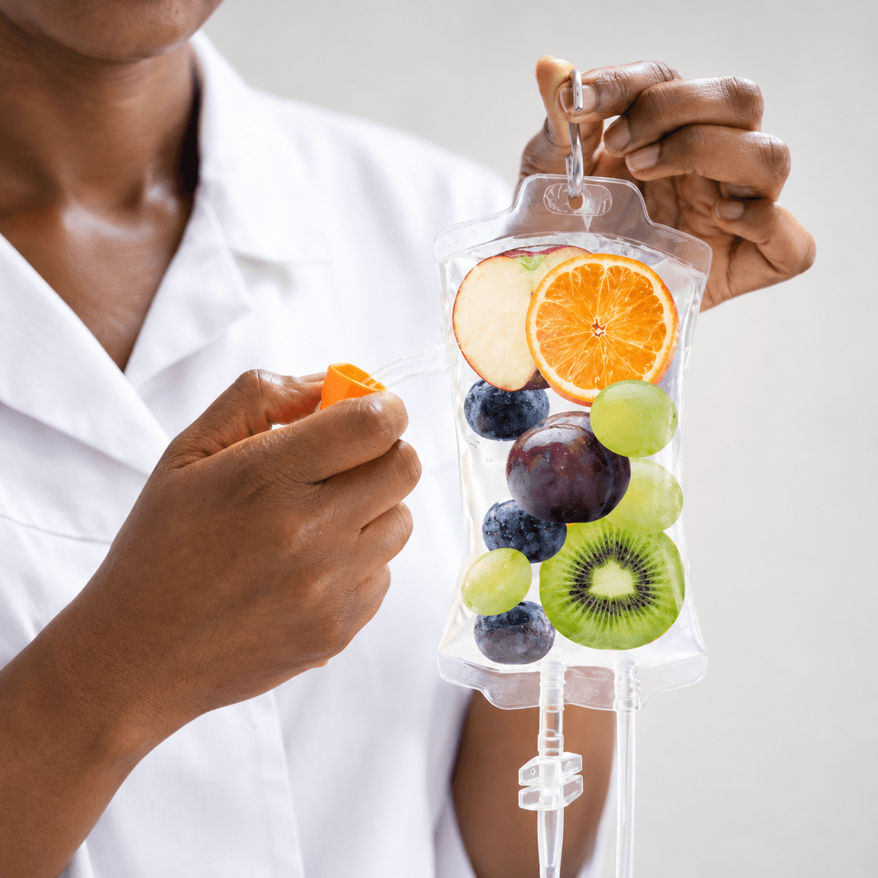 Healthcare provider holding an IV therapy bag with fruit imagery representing vitamins, hydration, and nutrients.