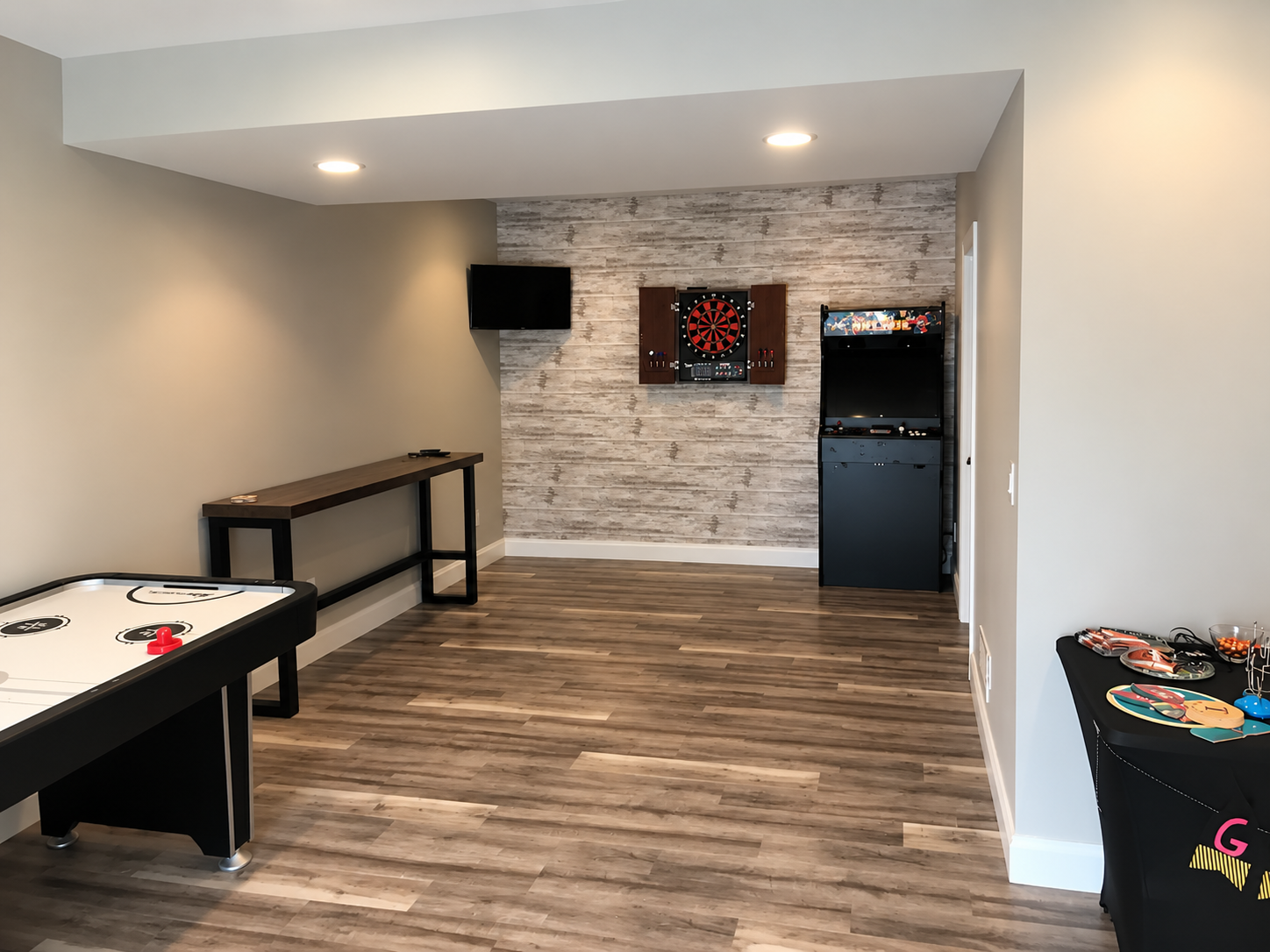 Finished basement game room with stone accent wall and recessed lighting by KingStruction