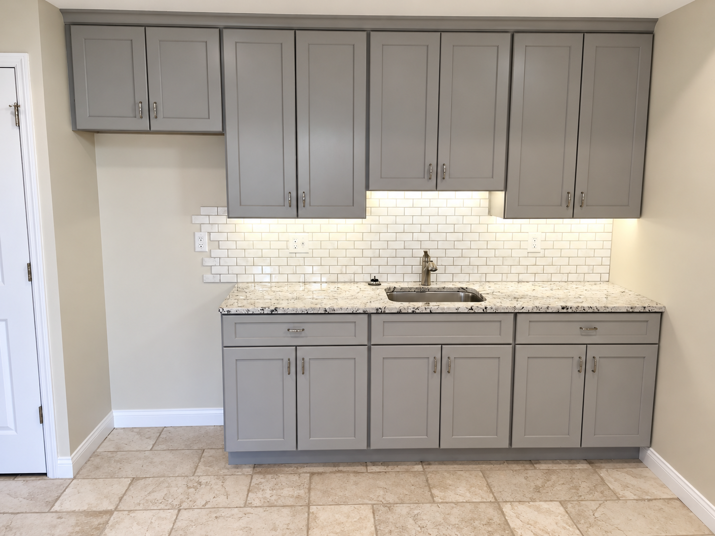 Basement wet bar with gray cabinetry, granite countertop, and subway tile by KingStruction