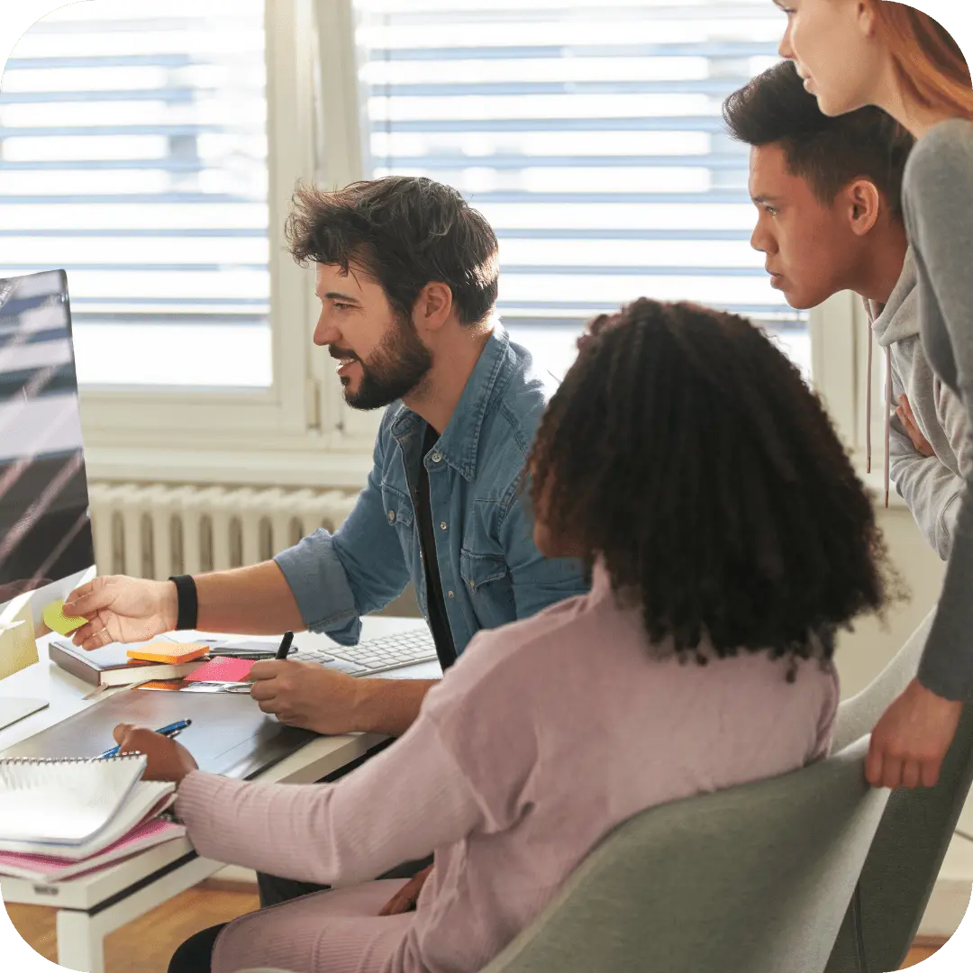 En gruppe designere som jobber med et prosjekt med støtte og veiledning fra en erfaren grafisk designer