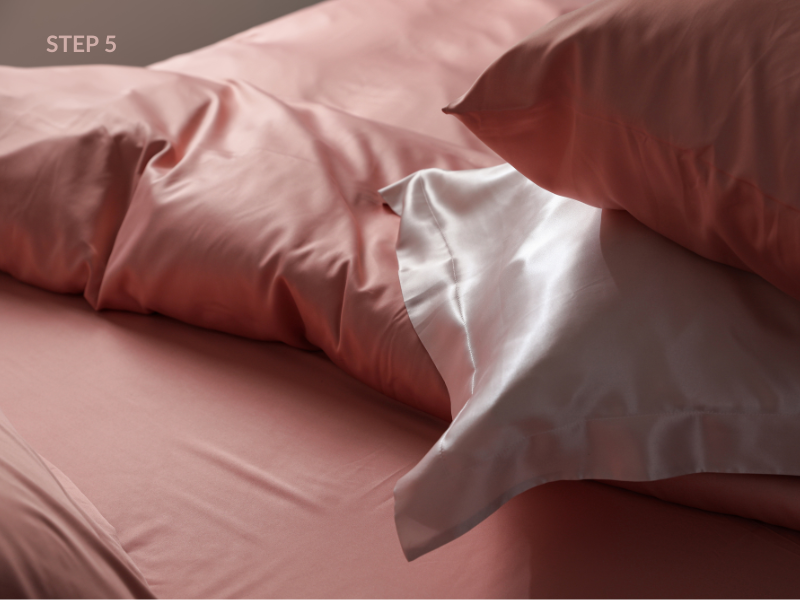 Luxury silk pillowcase on bed in blush pink — evening self-care routine for better sleep