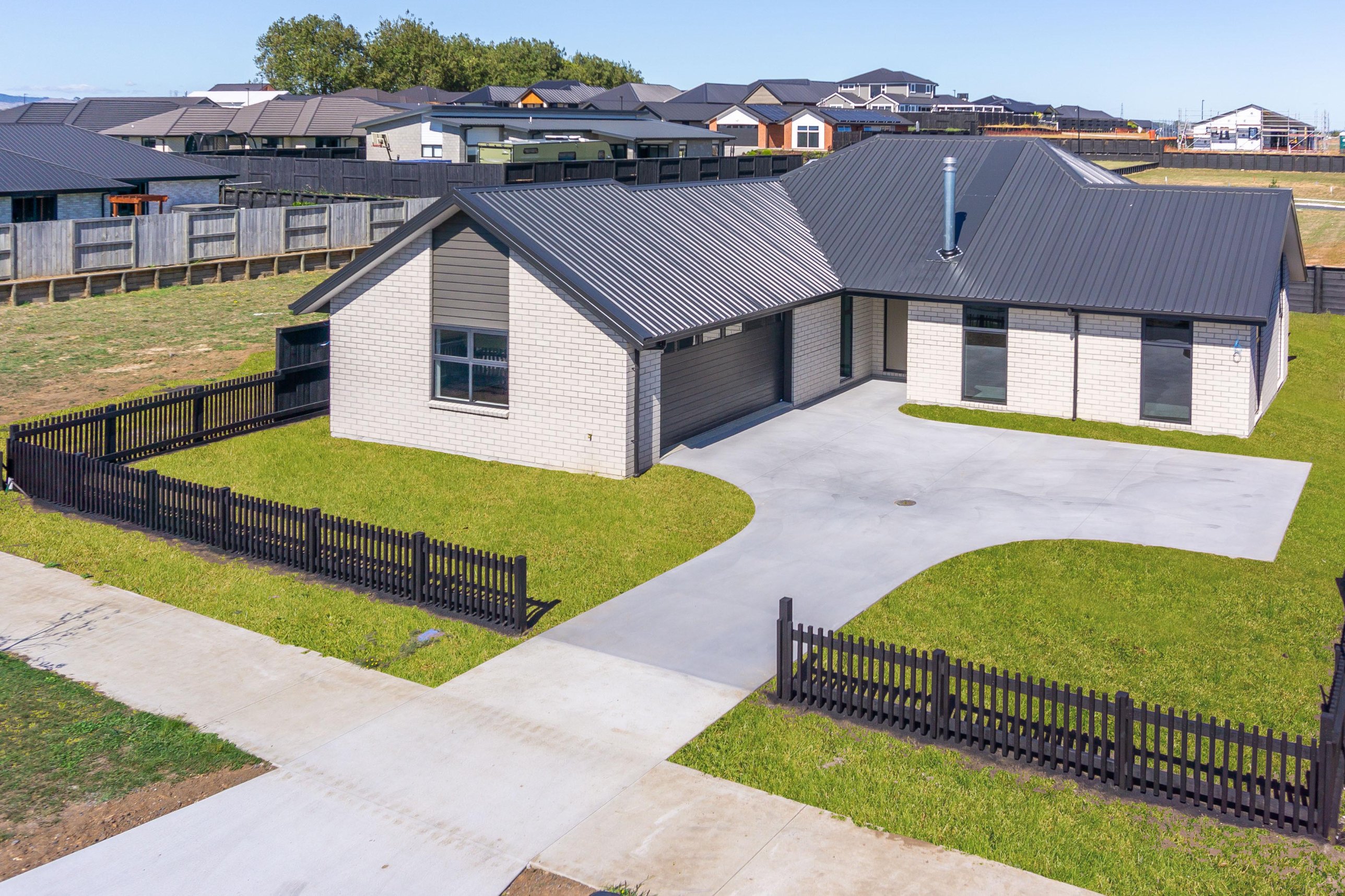Single-level brick home with double garage, fenced lawn and wide driveway, built by MH Builders in Lockerbie Estate, Morrinsville