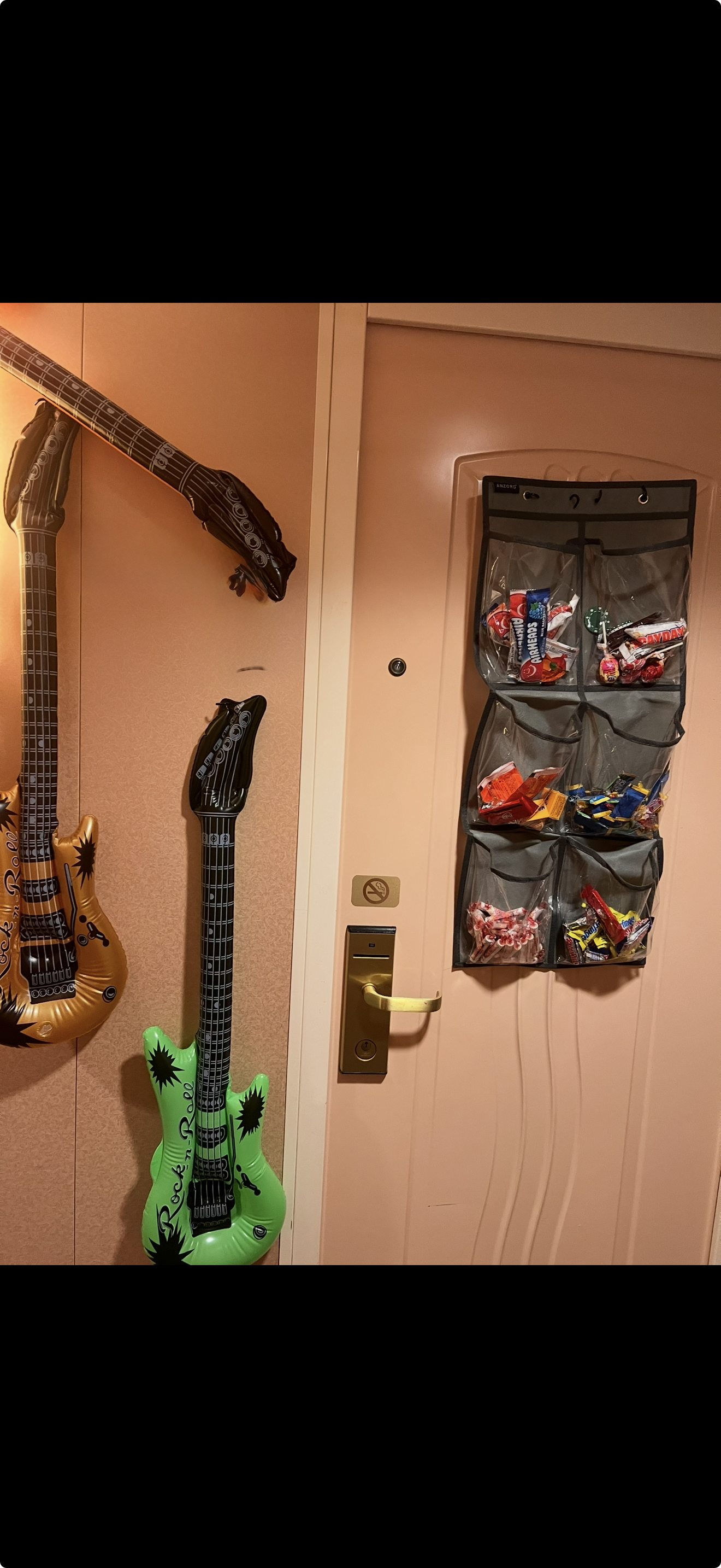 Cruise cabin hallway wall with inflatable rock and roll guitars and clear pocket candy organizer filled with snacks Cruise cabin hallway wall with inflatable rock and roll guitars and clear pocket candy organizer filled with snacks