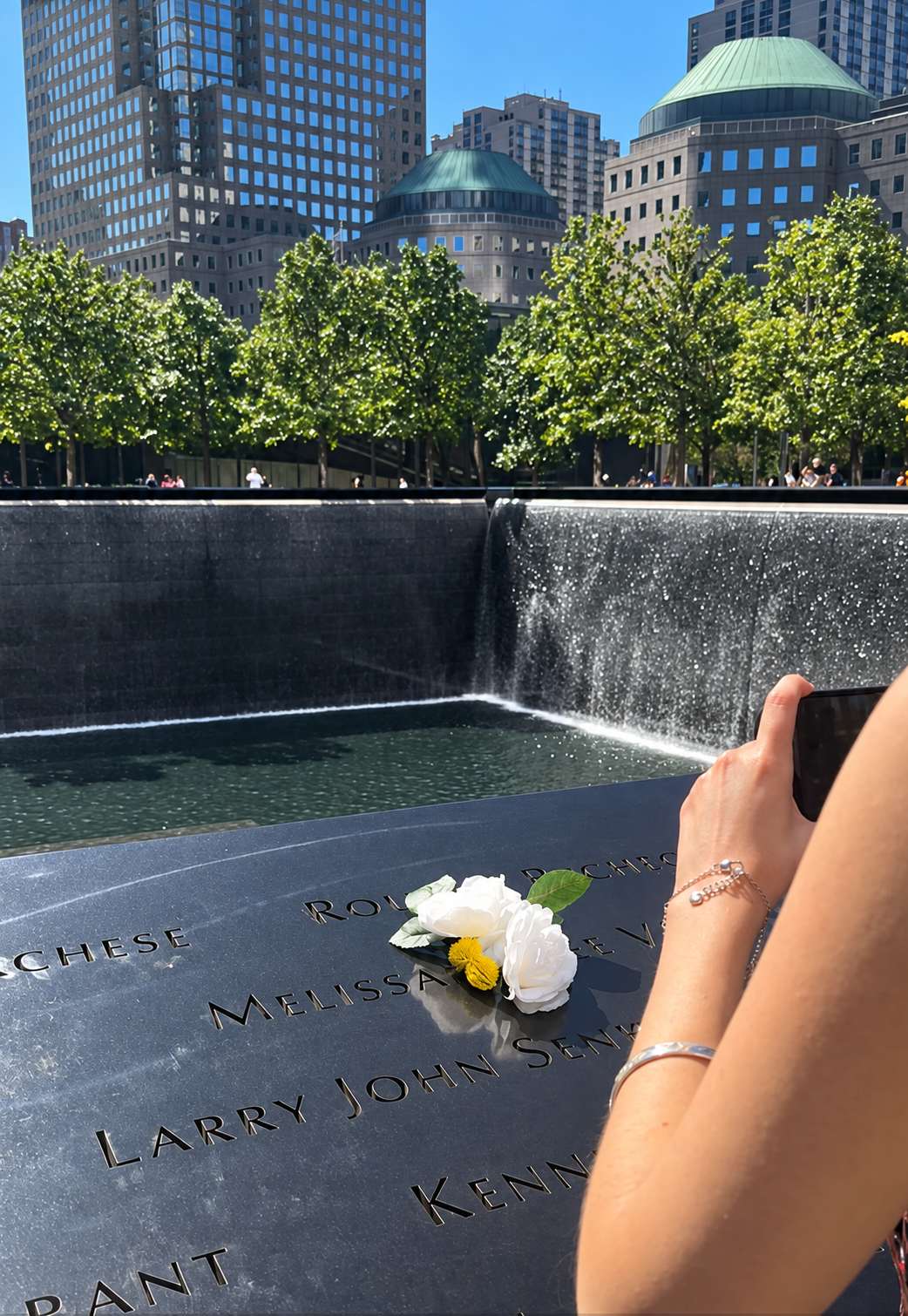 White flowers resting beside engraved names at the 9/11 Memorial reflecting pool in Lower Manhattan.