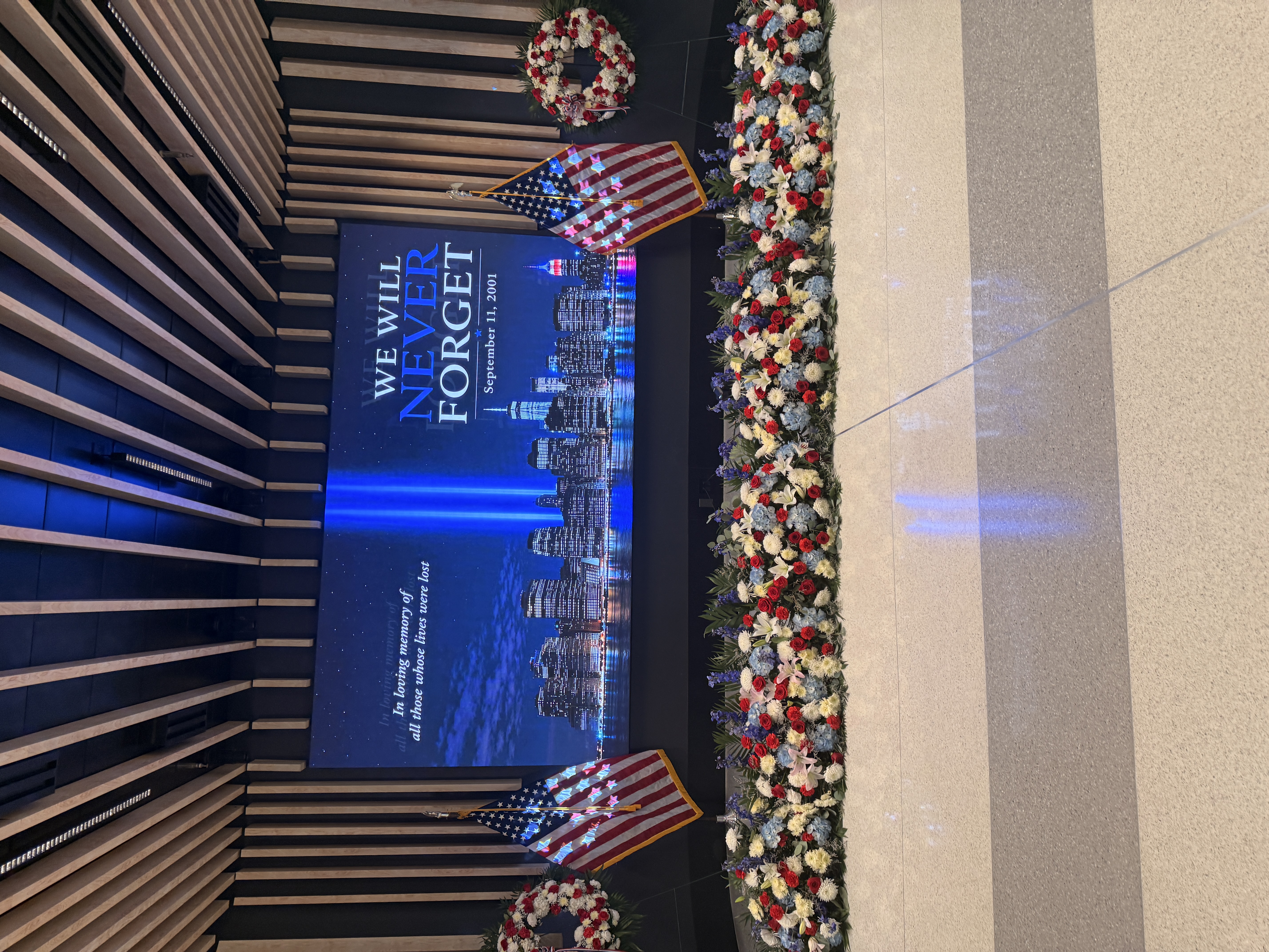 September 11 memorial display with American flags and flowers inside JFK Airport Terminal 8.