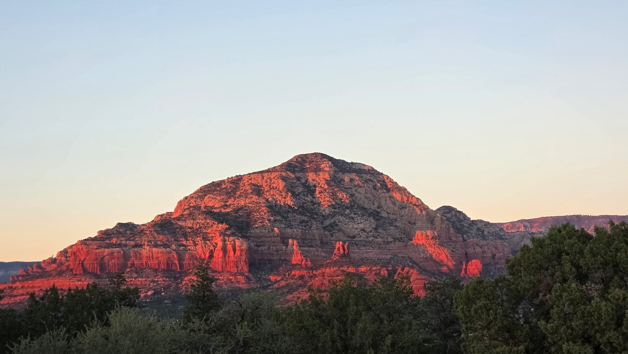 Red rock mountain glowing orange in the last light of sunset near Cultural Park Trailhead in Sedona, Arizona Red rock mountain glowing orange in the last light of sunset near Cultural Park Trailhead in Sedona, Arizona