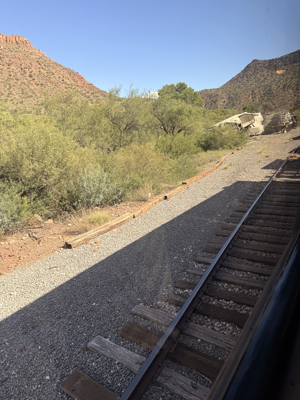 Railroad tracks wind through Verde Canyon, with desert vegetation and rocky hills in the distance Railroad tracks wind through Verde Canyon, with desert vegetation and rocky hills in the distance