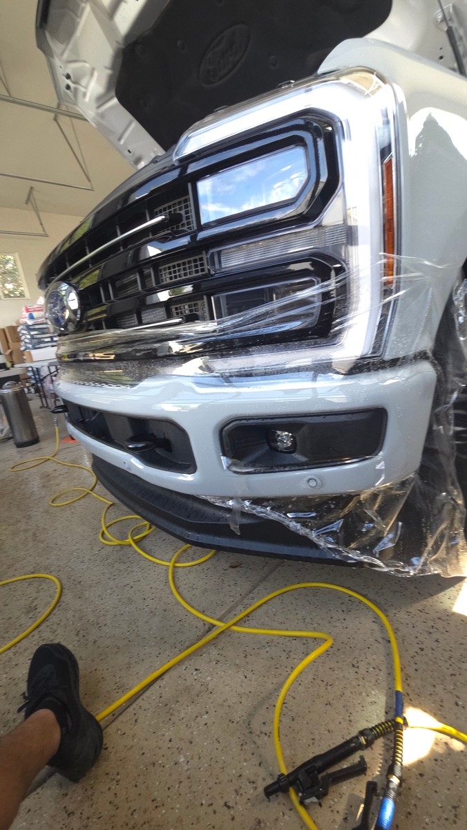 Ford F-350 grille and headlight area during paint protection film installation