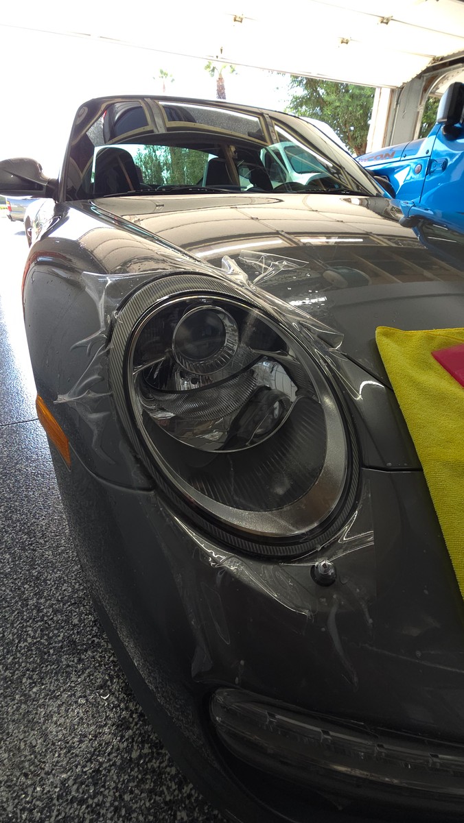 Protective film being fitted to a Porsche headlight.