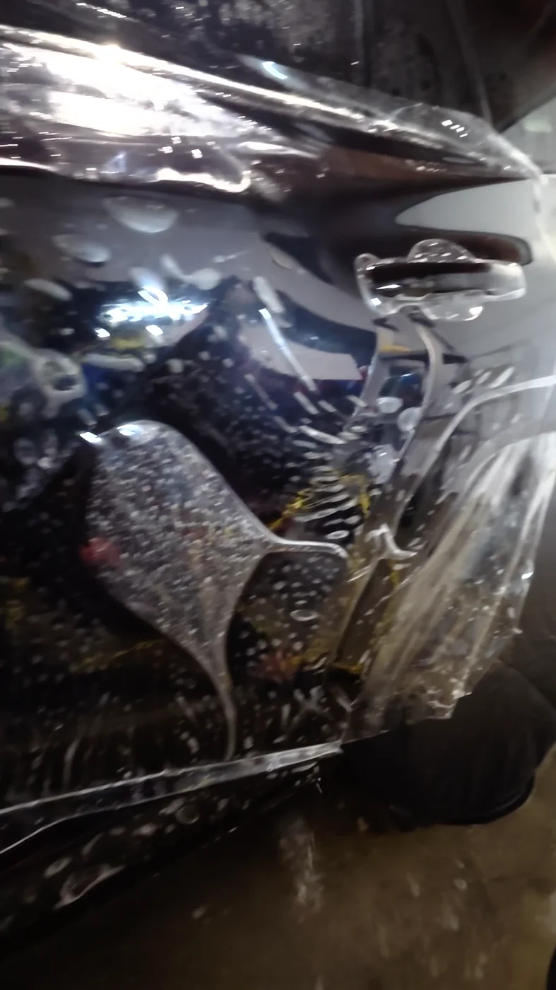 Loose clear paint protection film being fitted around the rear door of a dark blue Toyota RAV4.