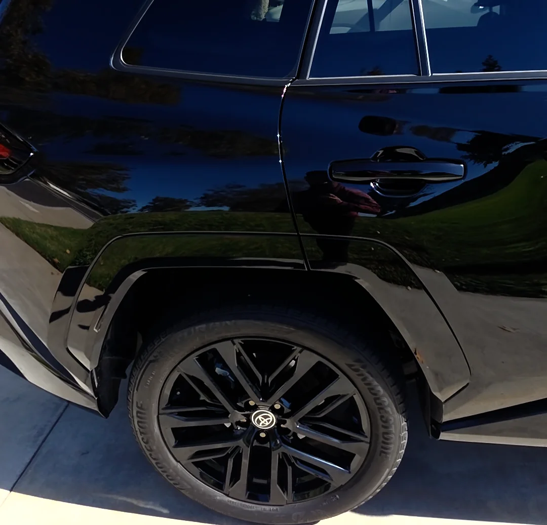 Rear quarter panel and rear wheel of the dark blue Toyota RAV4 outdoors after full-body PPF installation.