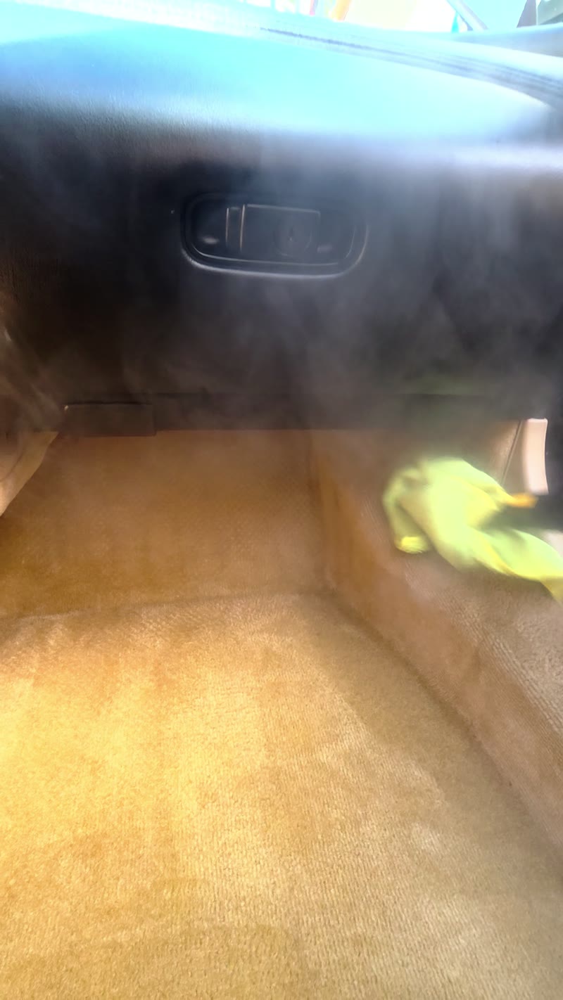 Steam and a gloved hand working in the beige passenger footwell of the Acura NSX.