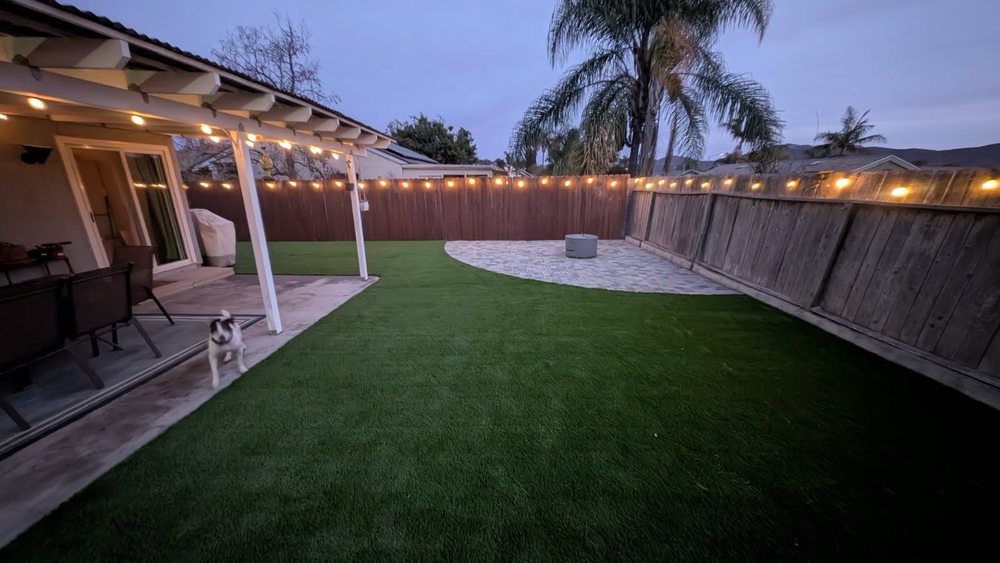Backyard with newly installed artificial turf and string lighting