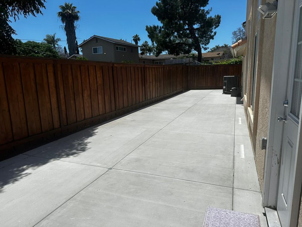 Long concrete side-yard patio along a stained wood fence
