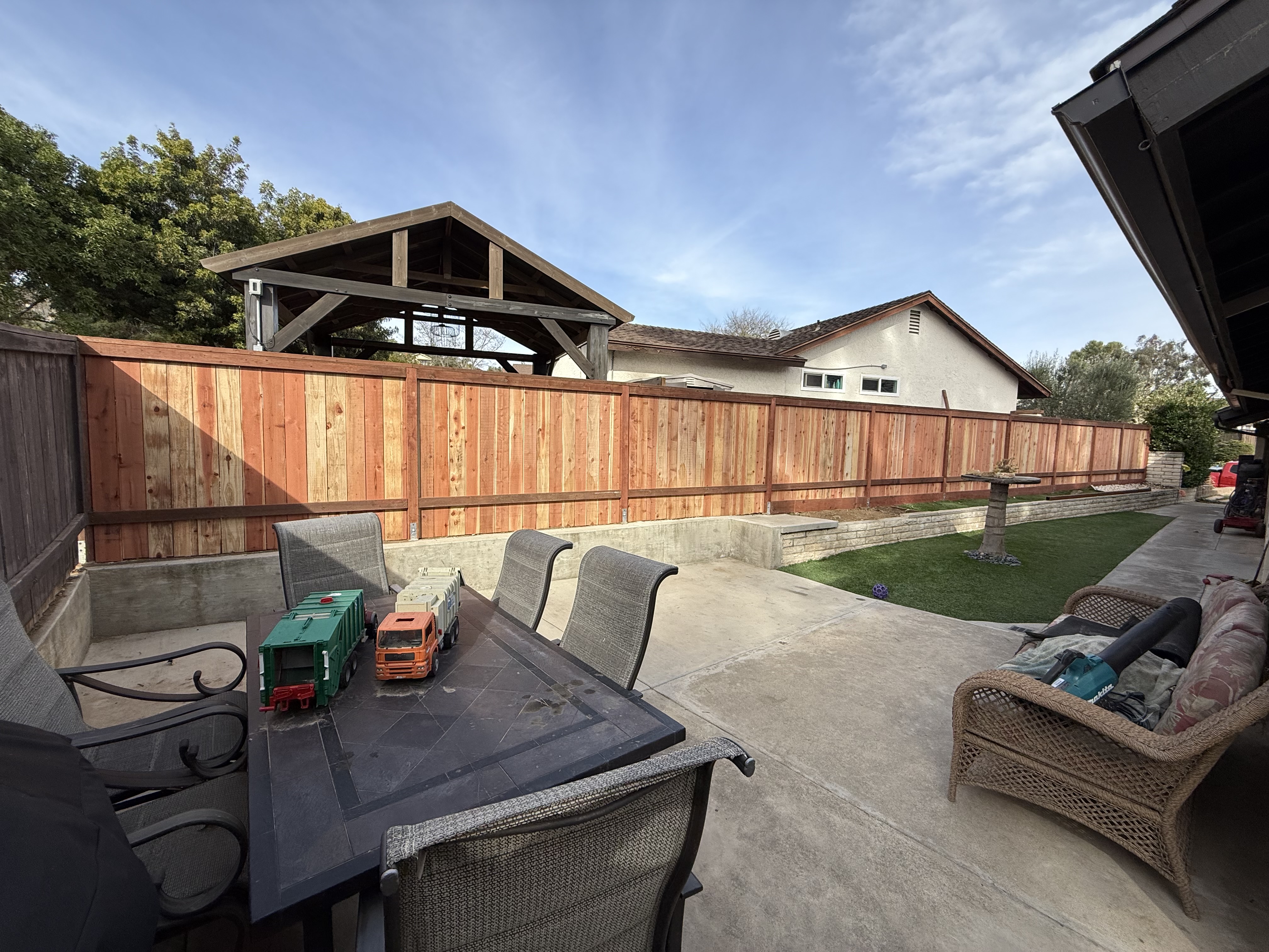 Backyard patio with new redwood fence and turf strip