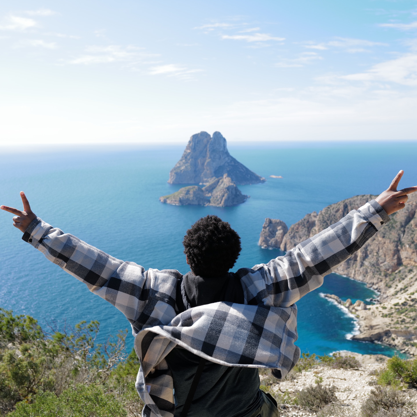 High achiever standing with open arms overlooking ocean and island vista