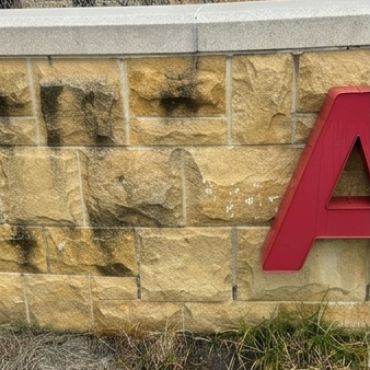 Before facade cleaning by WindowClean by Vertex showing stained stone wall with mildew and grime buildup