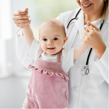 Baby standing with a pediatric doctor during a family-centered ear care consultation.