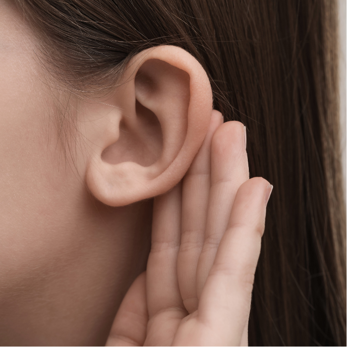 Child listening with a hand behind their ear, representing pediatric hearing loss, ear infections, and awake ear tube care.