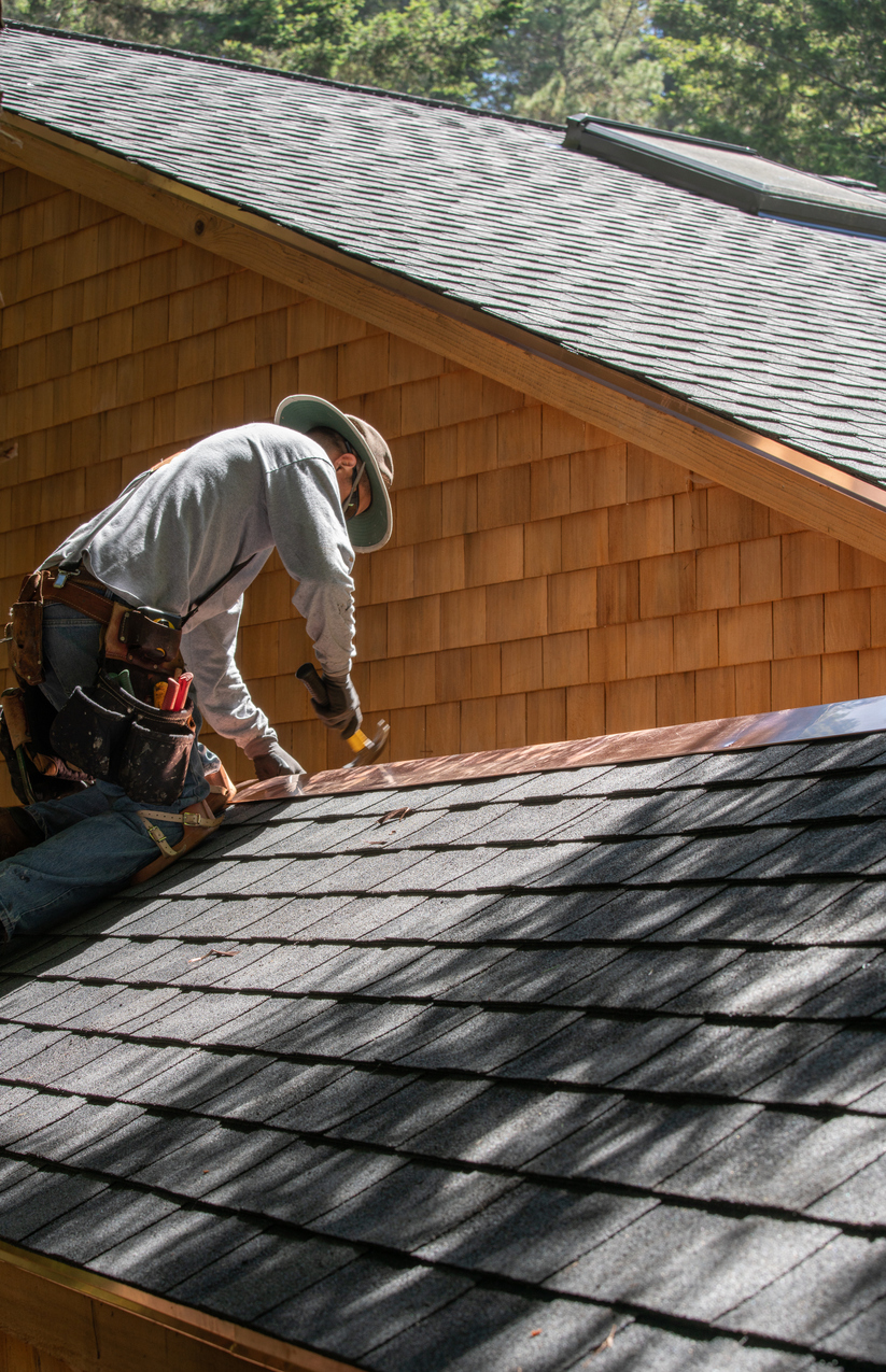 Roof repair specialist working on a shingle roof, showcasing professional roofing services in California by 