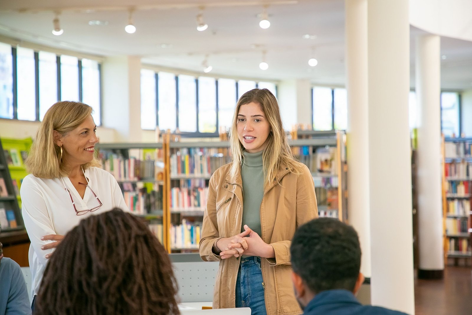 A Guide and a teenage learner talking with a studio group in a library