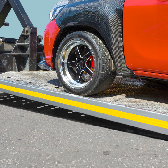 Red car being loaded onto a tow truck during roadside assistance.