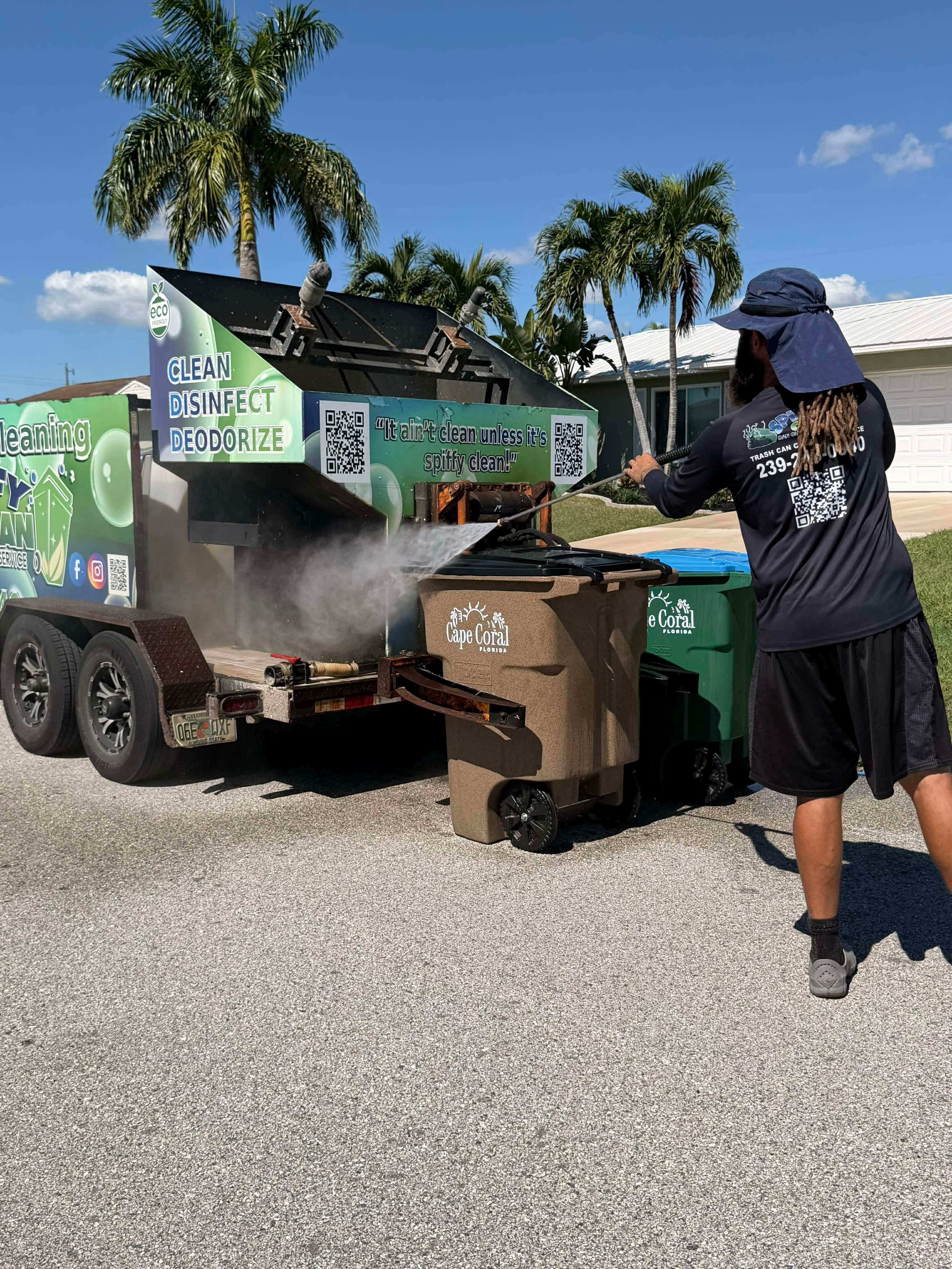 Technician performing professional trash can cleaning in Cape Coral, Florida using a high-pressure wash system mounted on a mobile cleaning trailer.