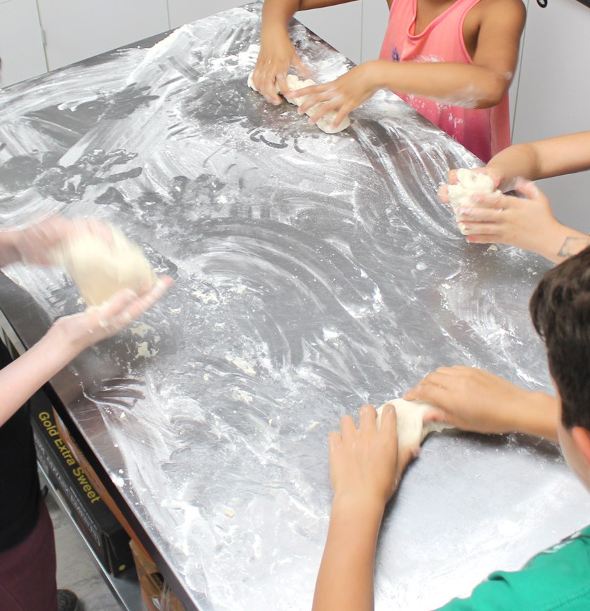 Hands kneading dough together during a school baking activity.