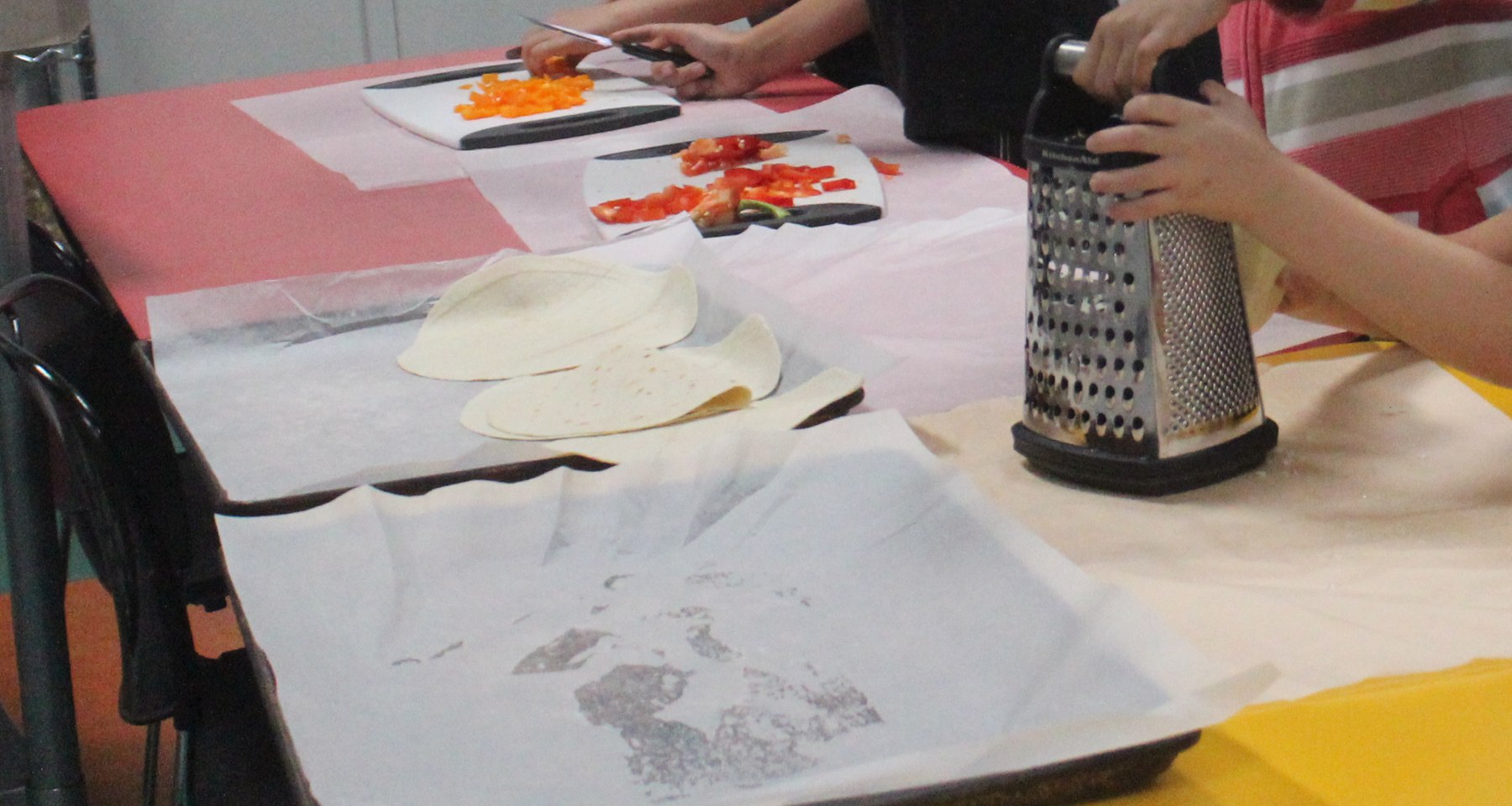 Hands preparing vegetables and ingredients during a school cooking activity