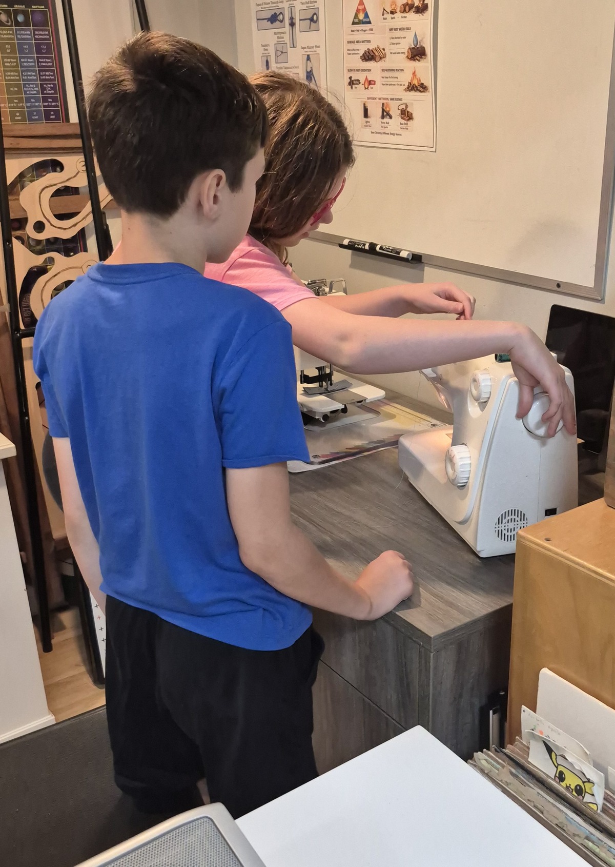 Two Evergreen students working together at a sewing machine in the Vaughan classroom.