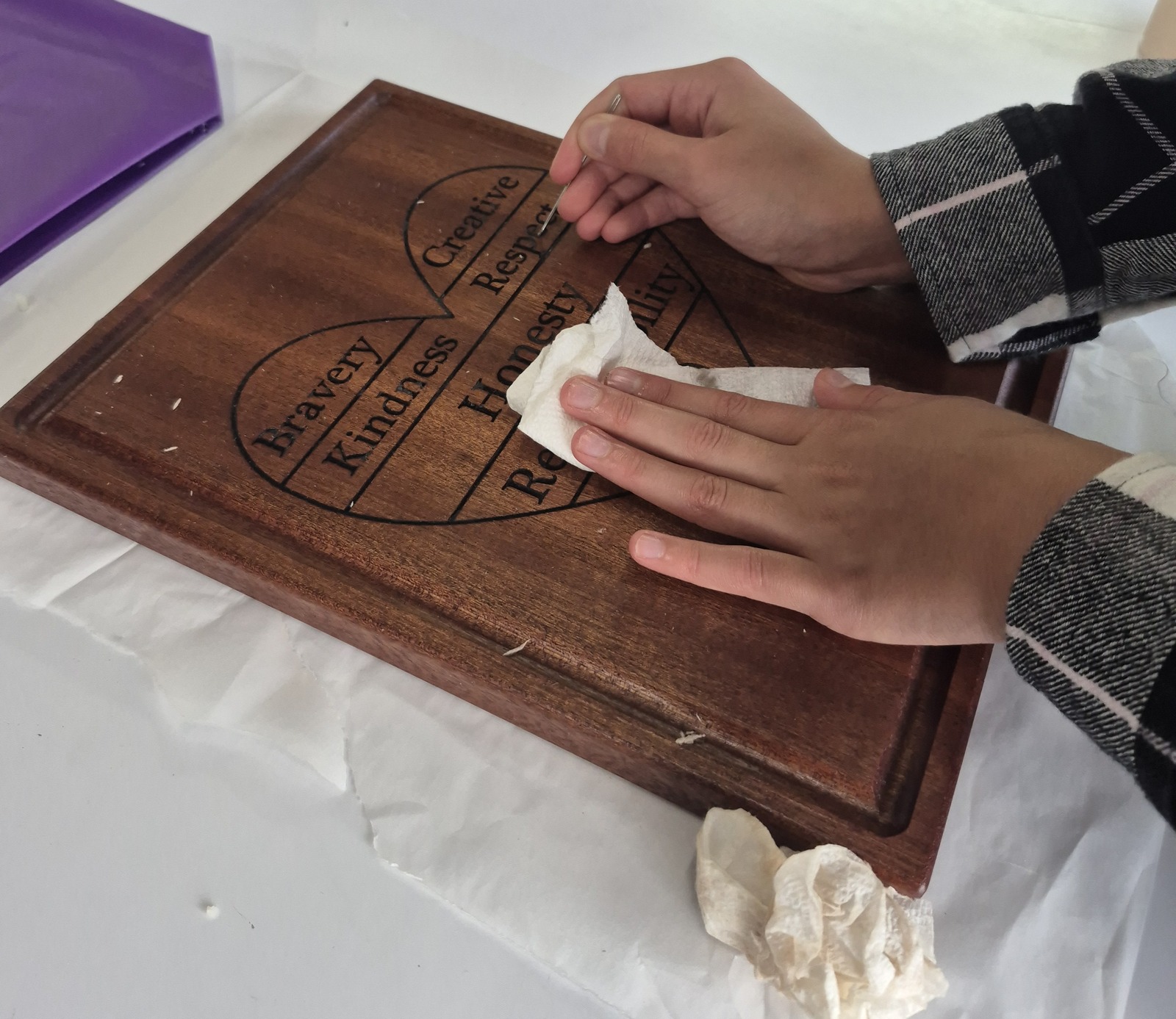 A student carefully finishing a wooden board as part of practical learning