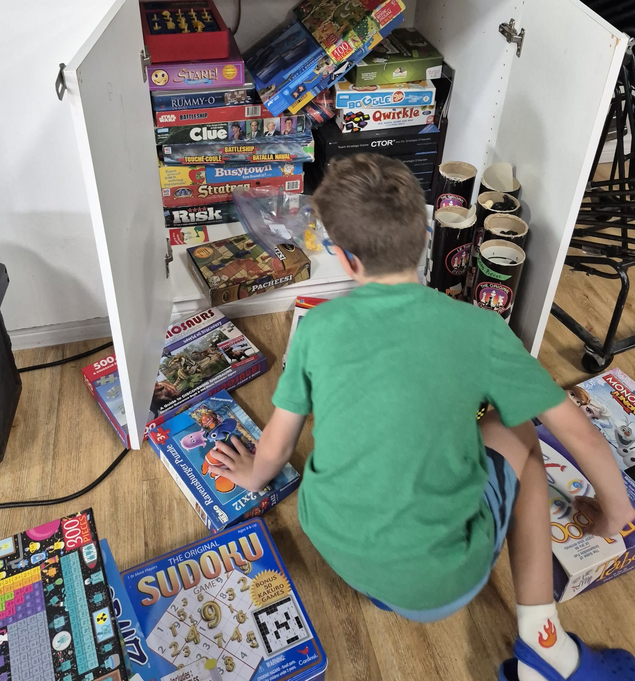 An Evergreen student organizing shared games and learning materials, photographed from behind.