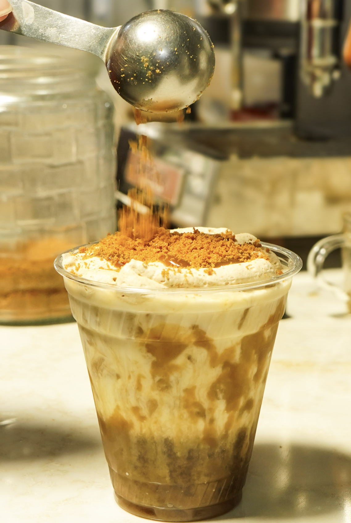 Iced specialty latte topped with whipped cream and cookie crumble