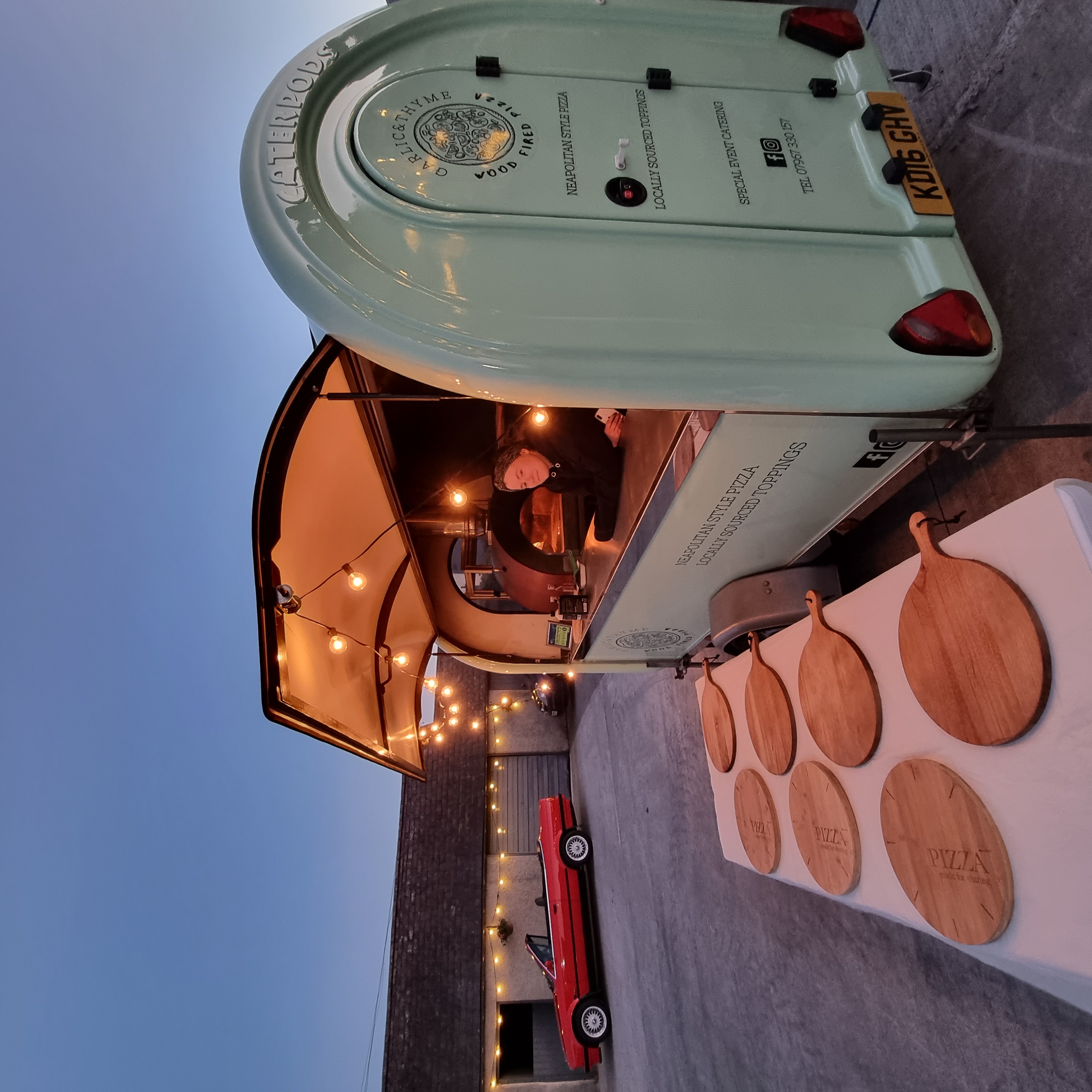 The Garlic and Thyme wood-fired pizza trailer lit and ready for an evening event