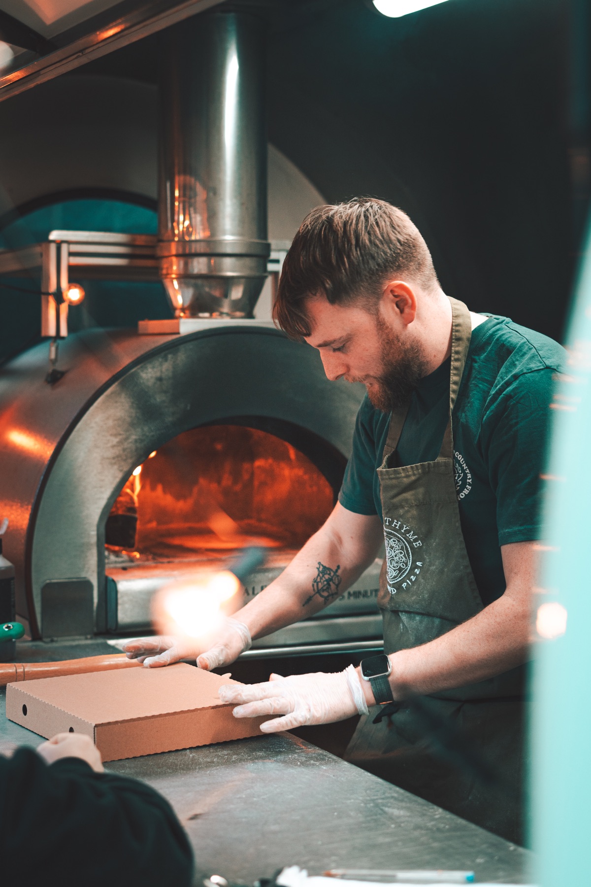 Rory, founder of Garlic and Thyme, working beside the lit wood-fired oven