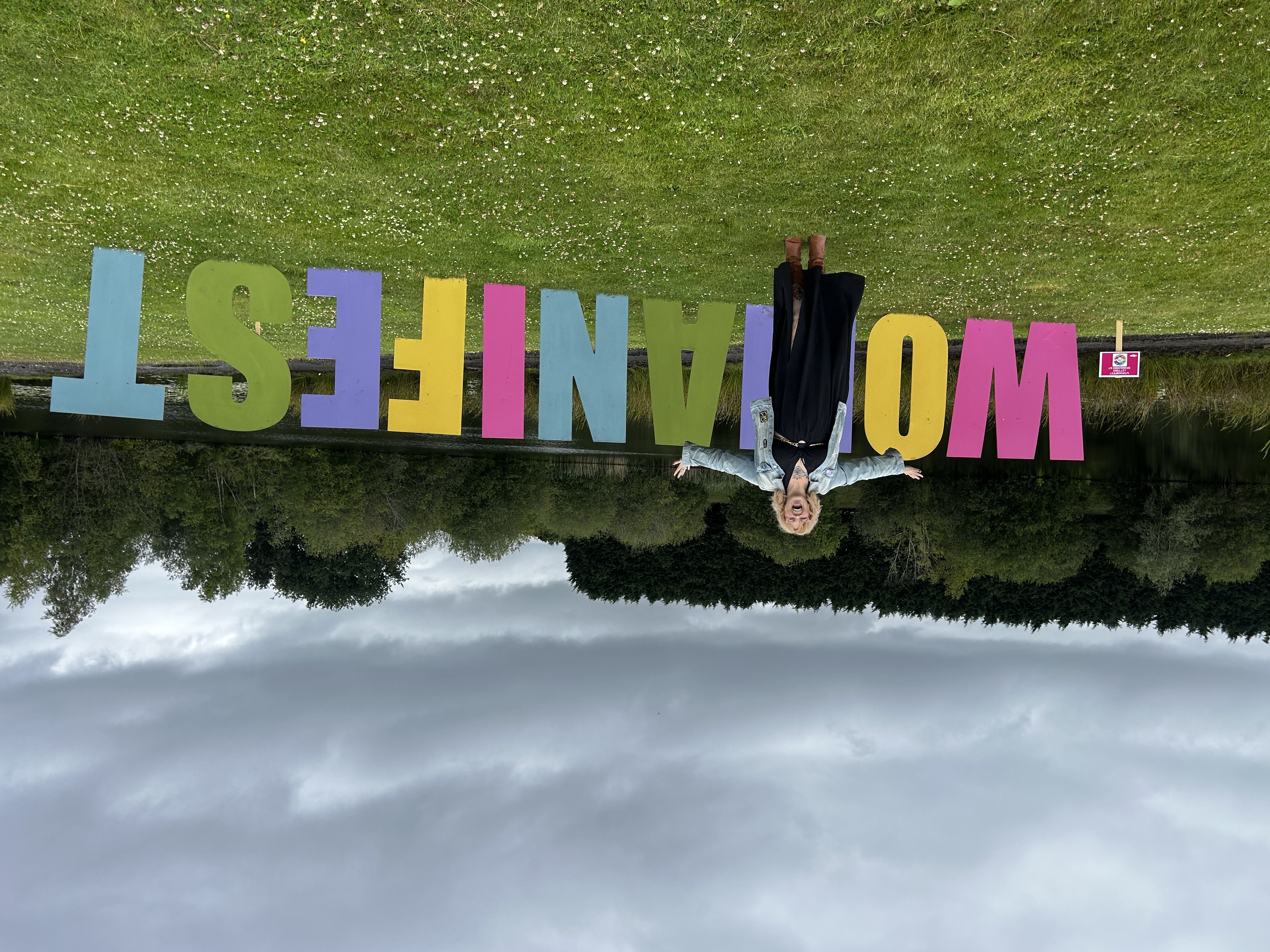 Kim Antrobus standing in front of giant colourful Womanifest letters
