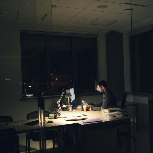 Man working late at night at desk with financial stress, representing poverty mindset and money anxiety Man working late at night at desk with financial stress, representing poverty mindset and money anxiety