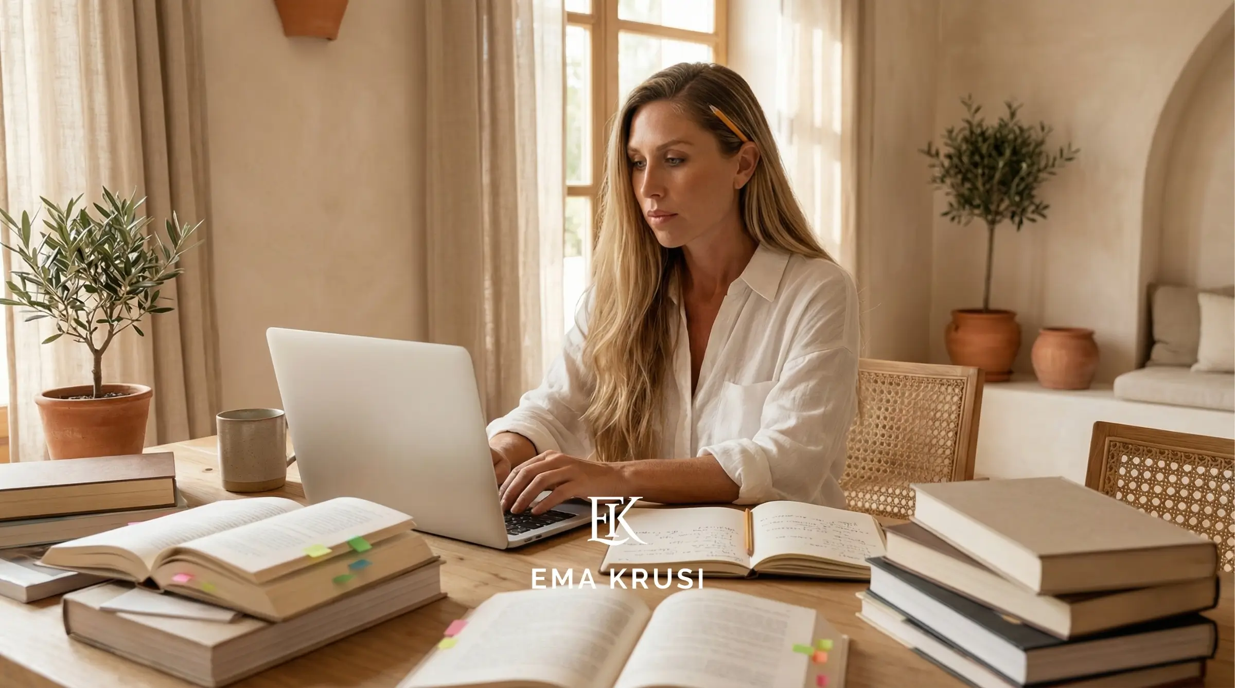 Femme travaillant sur un ordinateur portable entourée de livres et cahiers, dans un intérieur lumineux et naturel.