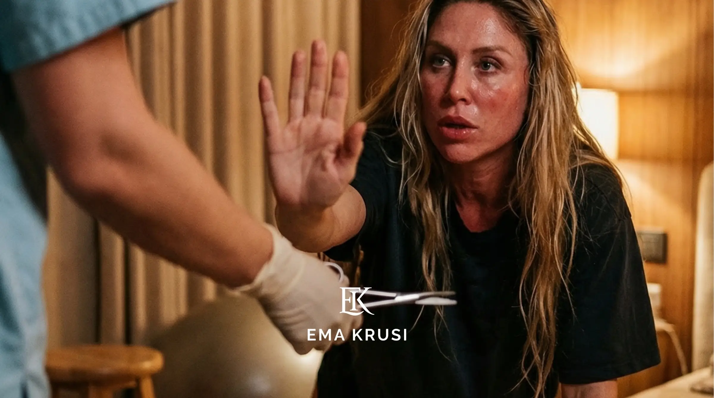 Femme en travail levant la main pour dire stop face à un soignant, dans une chambre à lumière chaude.