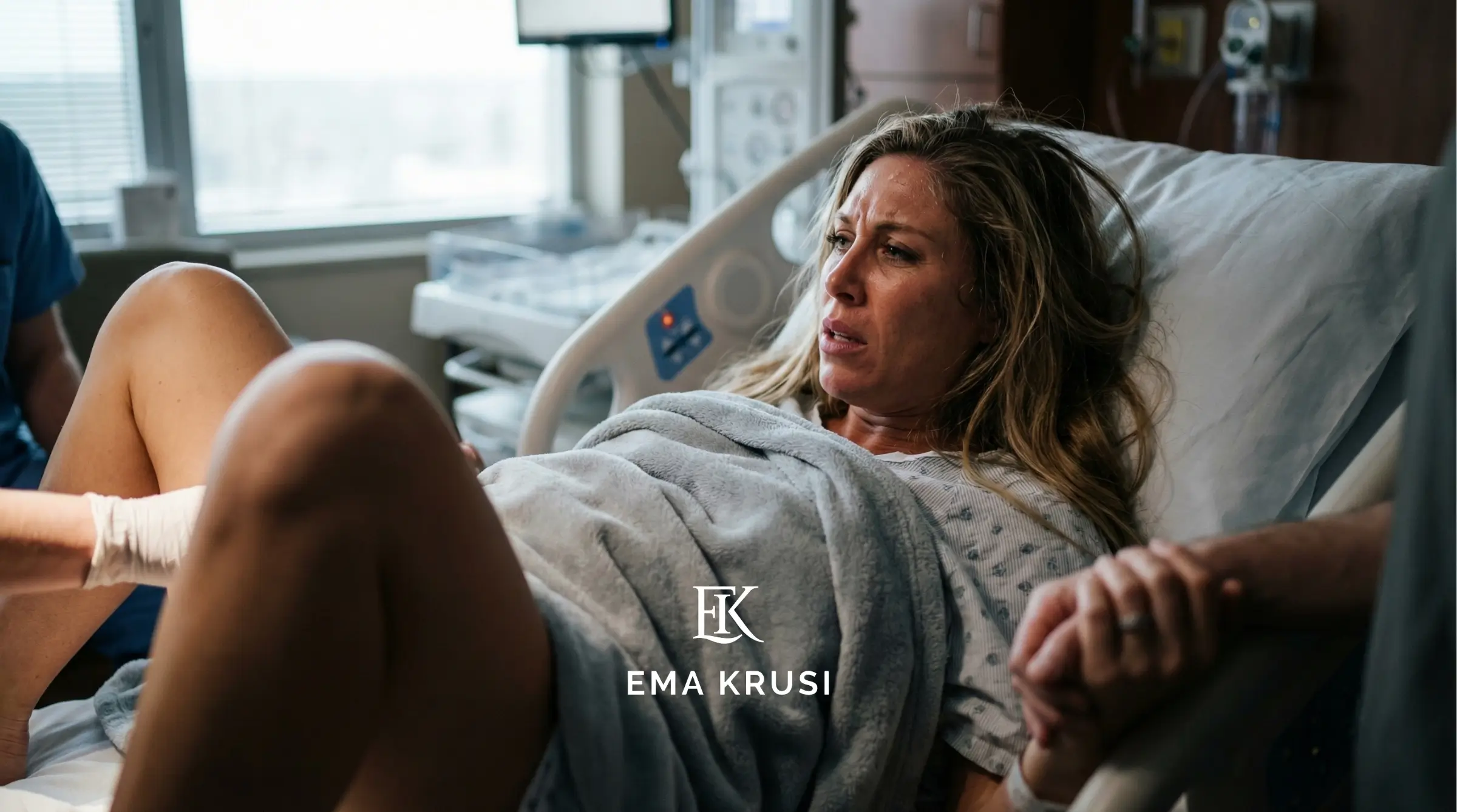 Femme en travail allongée sur un lit d’hôpital, respiration difficile, en salle de naissance.