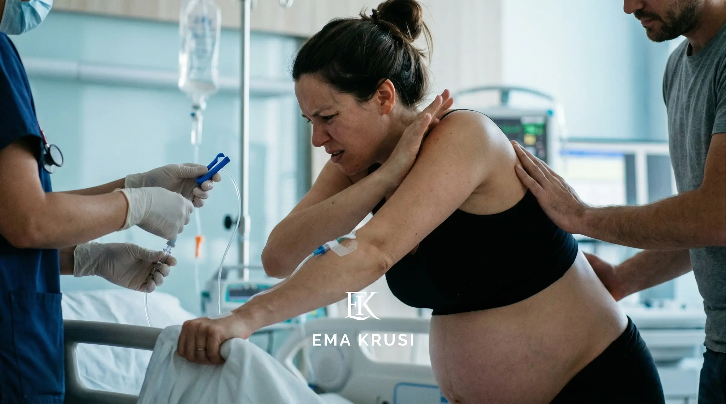 Femme en travail tenant un lit d’hôpital, perfusion au bras, soignant préparant une injection, partenaire la soutenant.