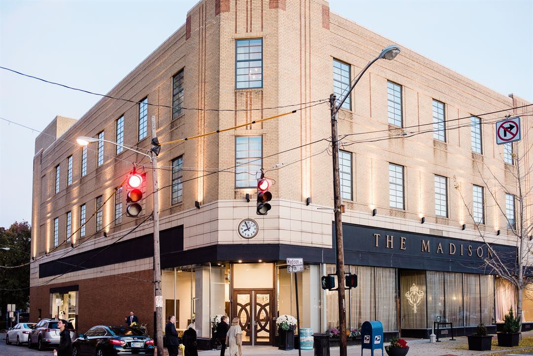 The Madison Event Center at dusk, gold lettering above the corner entrance on Madison Avenue