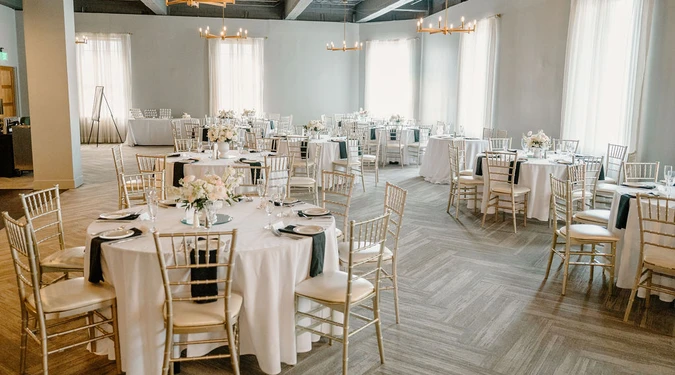 The main room set with round tables, gold chairs and black linens