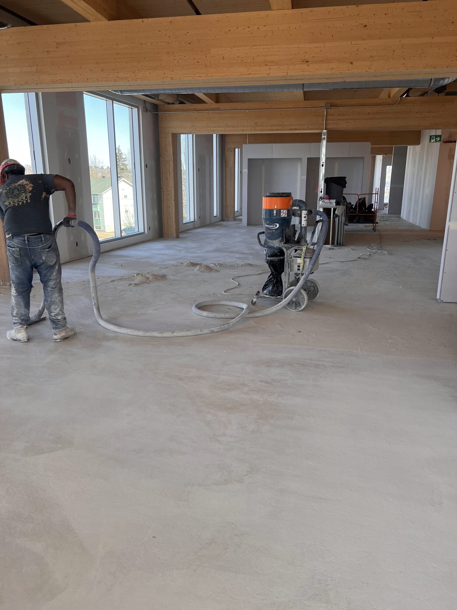 Crew mechanically preparing a concrete floor in a large interior