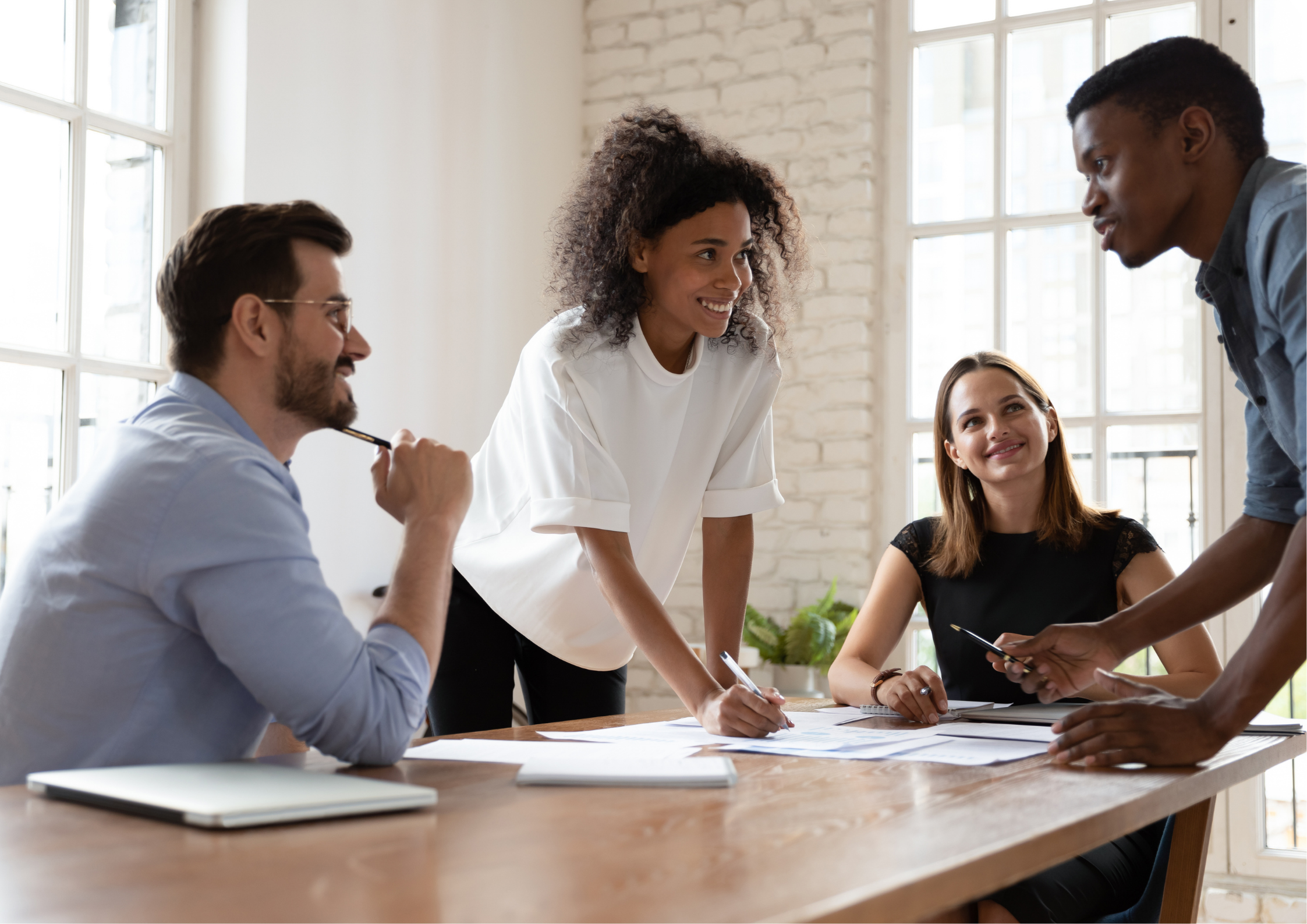 A diverse group of young professionals collaborating on a project during a meeting in a bright, modern office space.