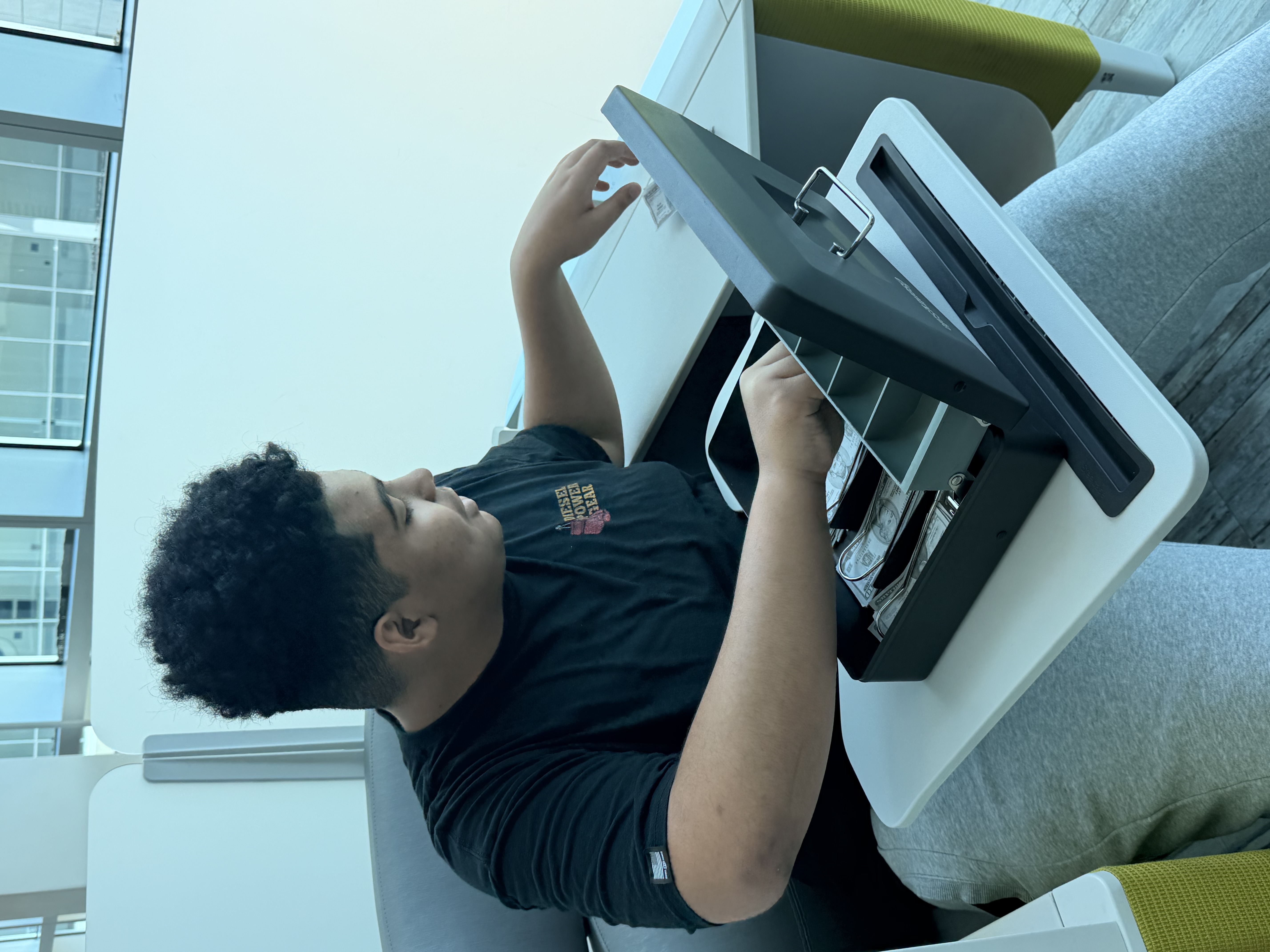 A student practicing cash handling and financial literacy tasks using a lockbox at Better Steps Life Skills Center.