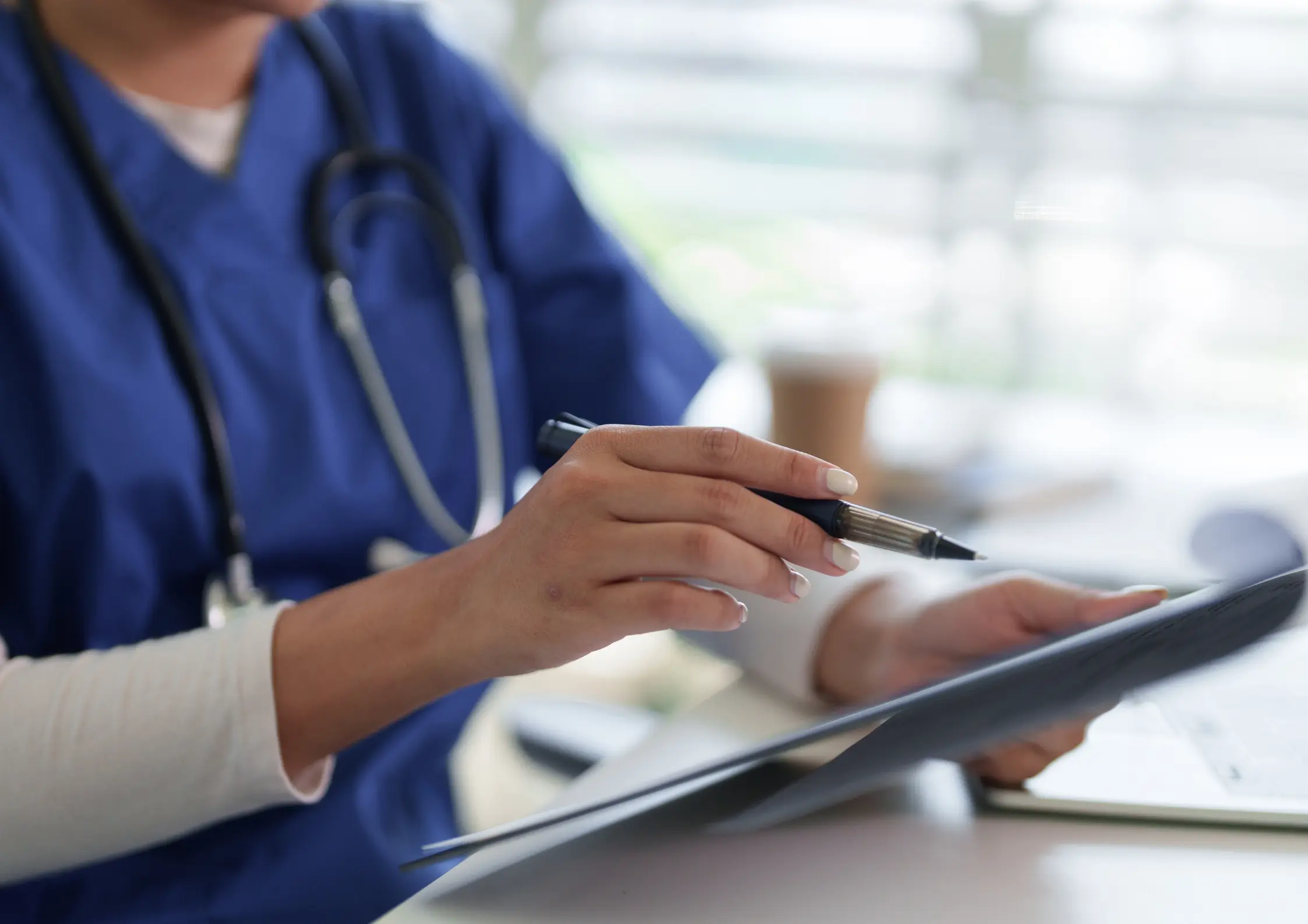A healthcare provider in scrubs reviewing medical documents to verify Medicaid and healthcare coverage benefits.