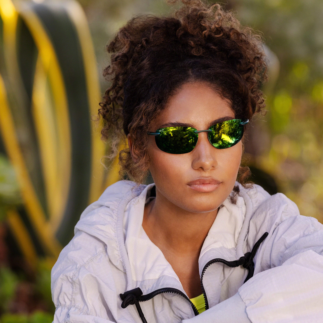 Woman wearing green mirrored Maui Jim sunglasses outdoors. Woman wearing green mirrored Maui Jim sunglasses outdoors.