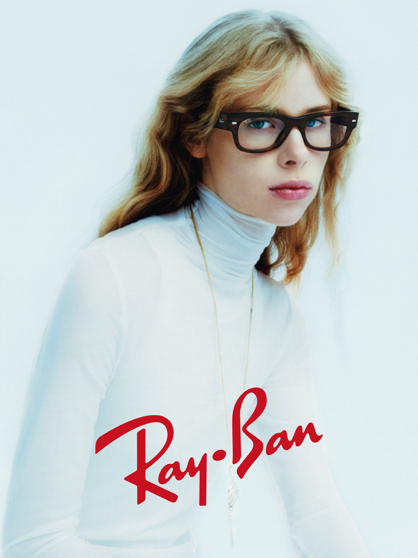 Woman wearing Ray-Ban dark brown acetate Wayfarer-style eyeglasses with clear lenses and a white turtleneck
