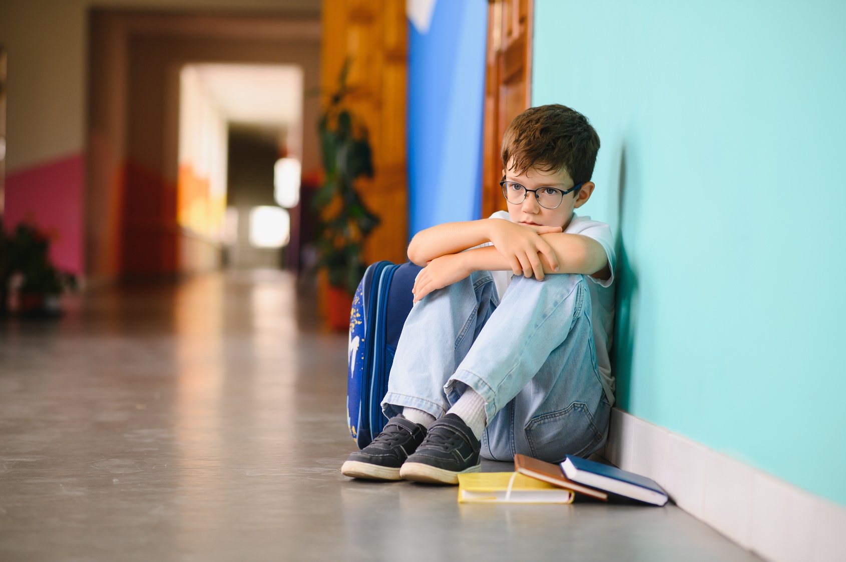 A boy sitting alone in a school hallway